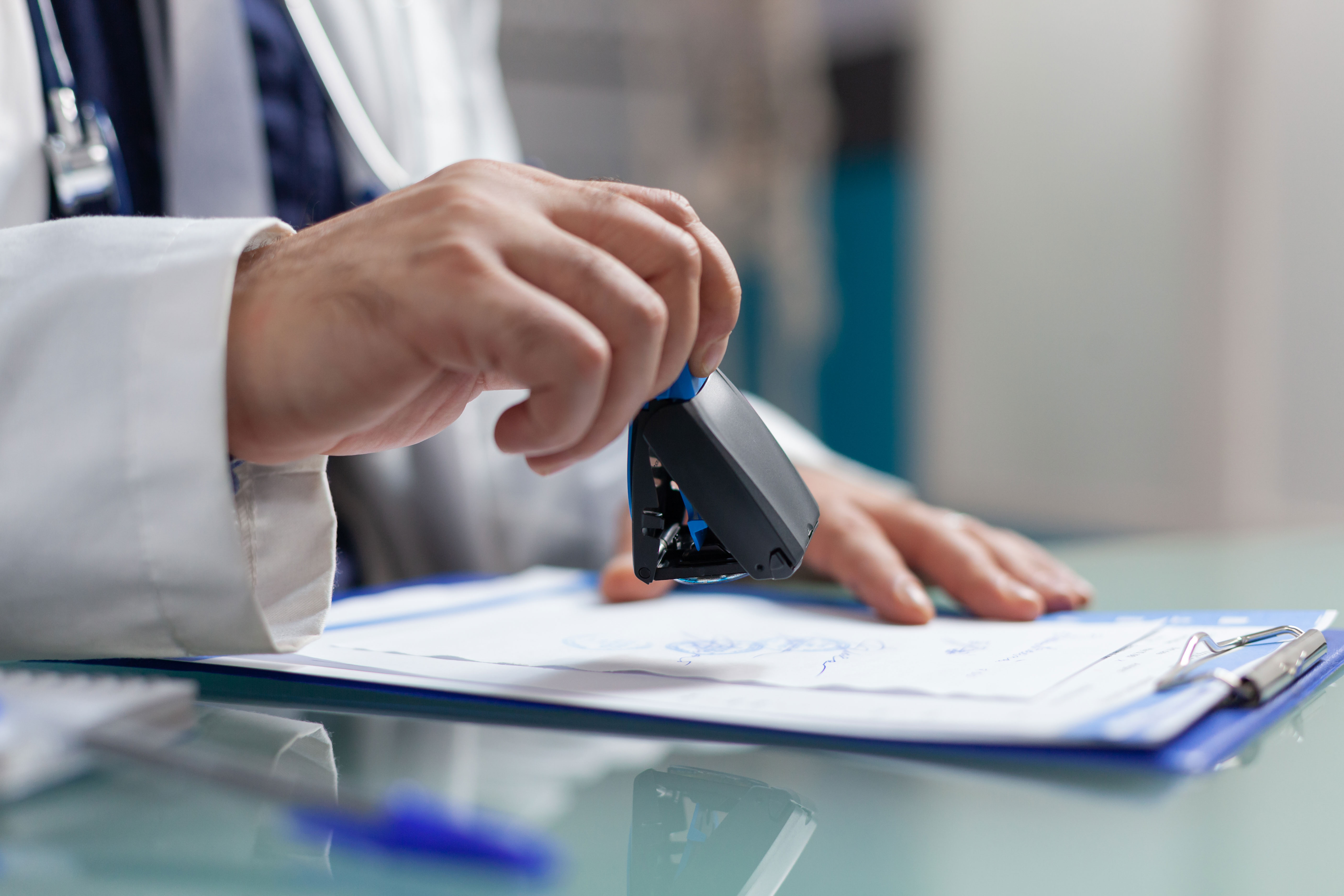 Hand of physician using medical seal on prescription paper