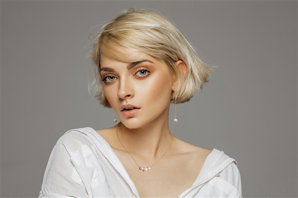 Portrait of beautiful blonde woman in white shirt and fashionable hairstyle